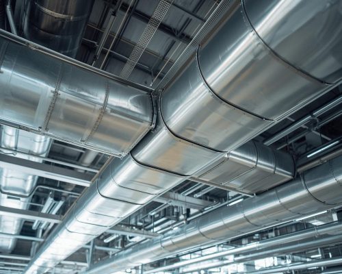 Industrial-style HVAC ducting system inside a commercial building. silver ducts running across ceiling, modern and sleek design, professional perspective shot.